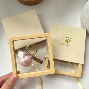 Detalle del colgante de tela rosa con bordado de flores de ciruelo y caja de regalo