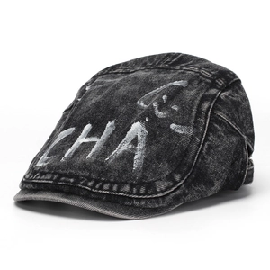 Close-up of vintage washed denim newsboy cap with white graffiti text and stitching