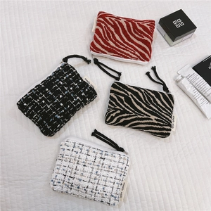 Macro view of four tweed and zebra print zipper pouches for cosmetics and earphones