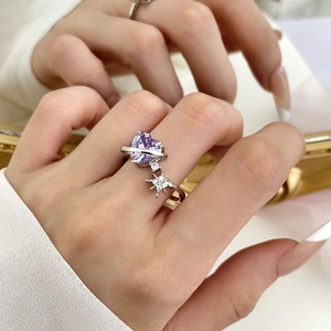 Detail of silver heart-shaped purple zircon ring with a small star pendant on a finger