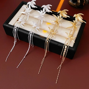 Detailed shot of gold and silver bamboo leaf tassel earrings on a velvet display stand