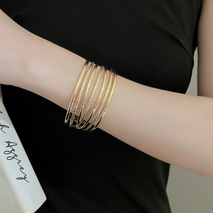 Detail of gold layered cuff bracelet with mixed smooth and textured metallic finish