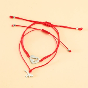 Detail of red woven couple bracelets with silver heart and airplane charm pendants