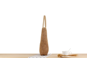 Detail view of khaki straw tote bag with woven mesh texture on a white background