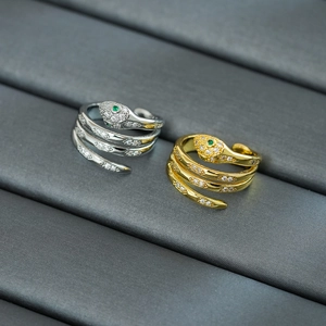 Detailed close-up of gold and silver snake rings with zircon stones and green gem eyes