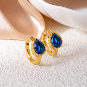 Detailed macro view of gold-plated hoop earrings with drop-shaped blue sapphire stones