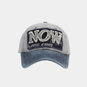 Details der Vintage-Baseballkappe aus gewaschener Baumwolle mit NOW-Stickerei und blauer Krempe