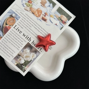 Detailed view of a red star hair clip with glossy patent finish on a cloud tray