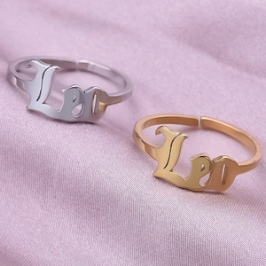 Macro detail of Leo zodiac sign rings in gold and silver finish on silk fabric