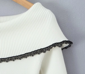 Detalle de blusa de punto acanalado blanco con encaje negro y bordes de volantes finos