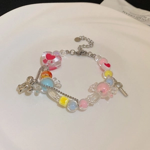 Détail macro du bracelet à perles macaron avec breloques cœur et nœuds sur une assiette en céramique