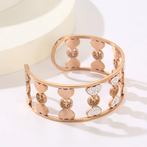 Detail of rose gold tree of life and heart-shaped bangle with white crystal accents