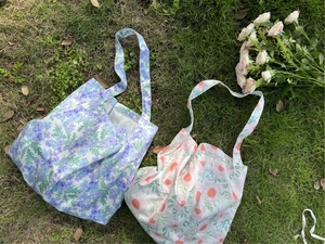 Detailed top view of floral cotton tote bags with shoulder straps on green grass