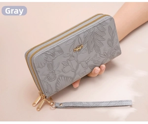 Detail of floral embossed leather texture on grey long wallet with golden zipper butterfly pull