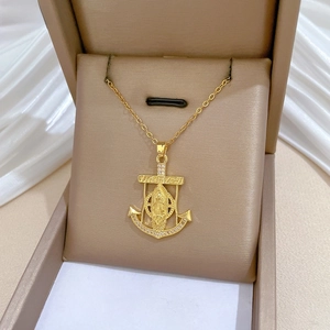 Detail of gold anchor pendant with religious relief and crystals in a beige jewelry box