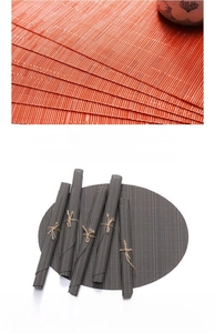 Detail of heat-cut edges on orange and grey PVC woven placemats with non-slip texture