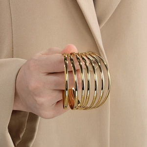 Close-up of stacking 18K gold-plated stainless steel bangles with polished finish