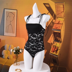 Detailed view of black lace bodysuit featuring thin straps and elegant paneling on a mannequin
