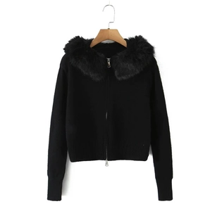 Detail of black knit cardigan featuring a plush faux fur collar and silver metal zipper