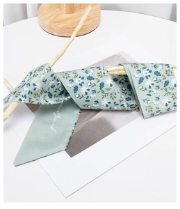 Detail of light green floral silk twilly scarf wrapped on a dry branch for styling