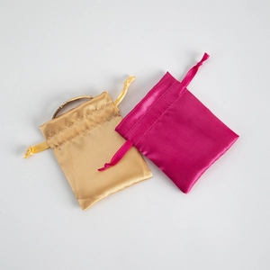 Golden and rose red satin drawstring bags for jewelry packaging on white background