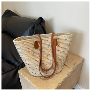 Detail of handwoven cotton tote bag with colorful polka dots and slim brown leather straps
