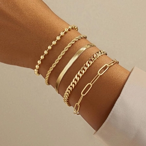 Close-up of five layered gold metal chains including Cuban, snake and paperclip styles