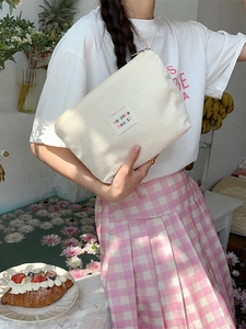 White vintage corduroy cosmetic bag with zipper being held in a natural setting