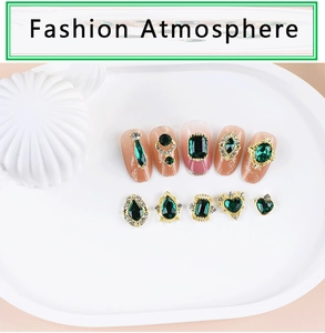 Detail of luxury emerald gemstone nail art charms with gold trim and rhinestones