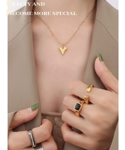 Detail of 18K gold-plated heart necklace and minimalist ring set on a model