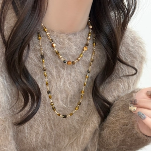 Collier double couche en perles œil de tigre aux tons ambre et marron sur pull marron