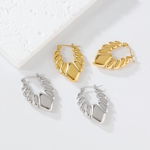 Detail view of gold and silver shrimp style ribbed hoop earrings on white textured stone