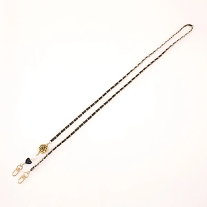 Detail of woven black leather and gold chain strap with camellia and pearl charms