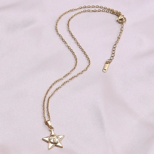 Detailed view of a gold sun face star pendant with O-chain on elegant pink silk background
