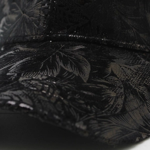 Détail du motif de feuilles tropicales brillantes et des coutures sur la casquette noire