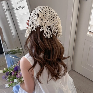 Detail of cream crochet triangle headscarf with hollow diamond pattern and long tassels