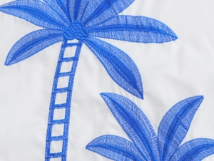 Detailed close-up of blue palm tree embroidery on white vacation two-piece set fabric