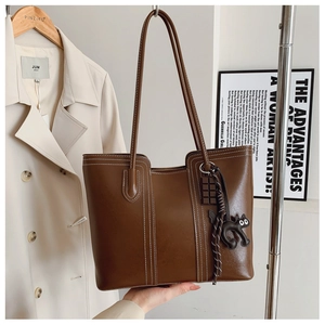 Close-up of deep brown tote bag featuring white contrast stitching and cute charms