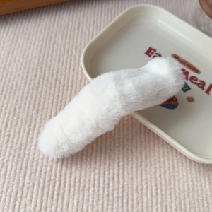 Close-up of a white plush hair clip on a decorative tray showing its soft fuzzy texture