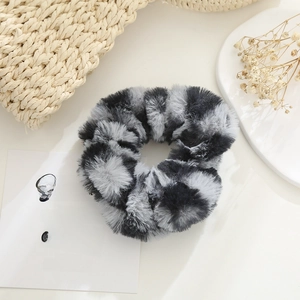 Detail of plush faux fur hair scrunchie with soft grey and black texture in cozy setting