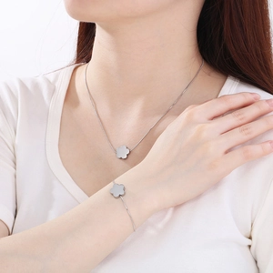 Silver four-leaf clover necklace and bracelet set shown on model in natural light