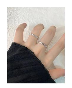 Detailed view of silver minimalist smile and heart pattern rings on a hand