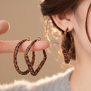 Stylish leopard print hoop earrings with suede texture on model in warm lighting