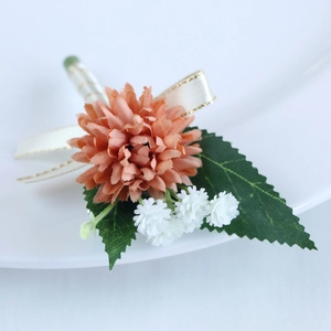 Exquisite orange wedding boutonniere with silk ribbon and greenery on white background