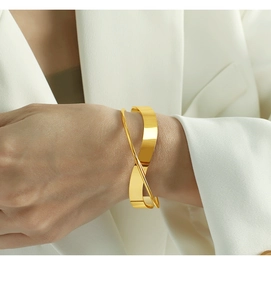 Detailed view of irregular crisscross wide open bangle in polished golden metal