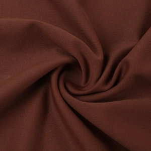 Gros plan du tissu tricoté marron foncé montrant la texture fine et le drapé soyeux