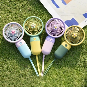 Cute cartoon flower mini handheld fans in pastel colors on green grass background
