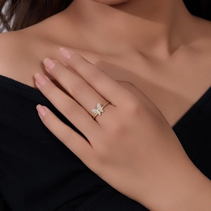 Close-up of a minimalist gold butterfly ring with sparkling zircons worn on hand