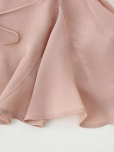 Dettaglio dell'orlo di una camicia di raso rosa con tessuto strutturato e pieghe