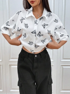 Detalle del estampado de mariposa negra en camisa blanca de manga corta con botones
